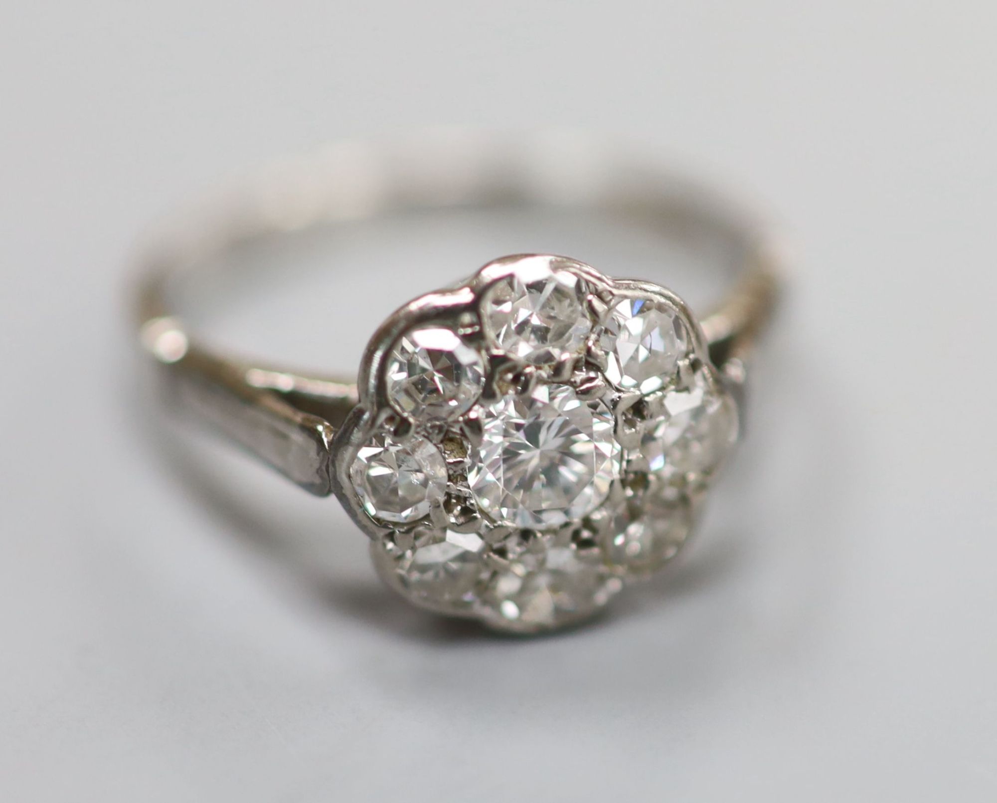 A mid 20th century white metal (stamped platinum) and nine-stone diamond set cluster ring, size K, gross 3 grams.